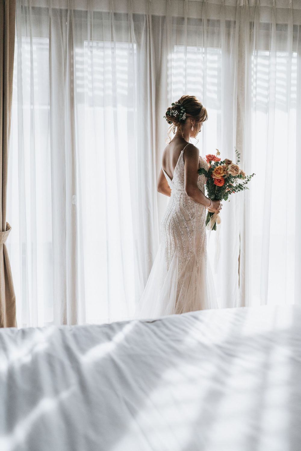 Sunlit bridal preparation room with flowing white curtains creating a dreamy atmosphere.
