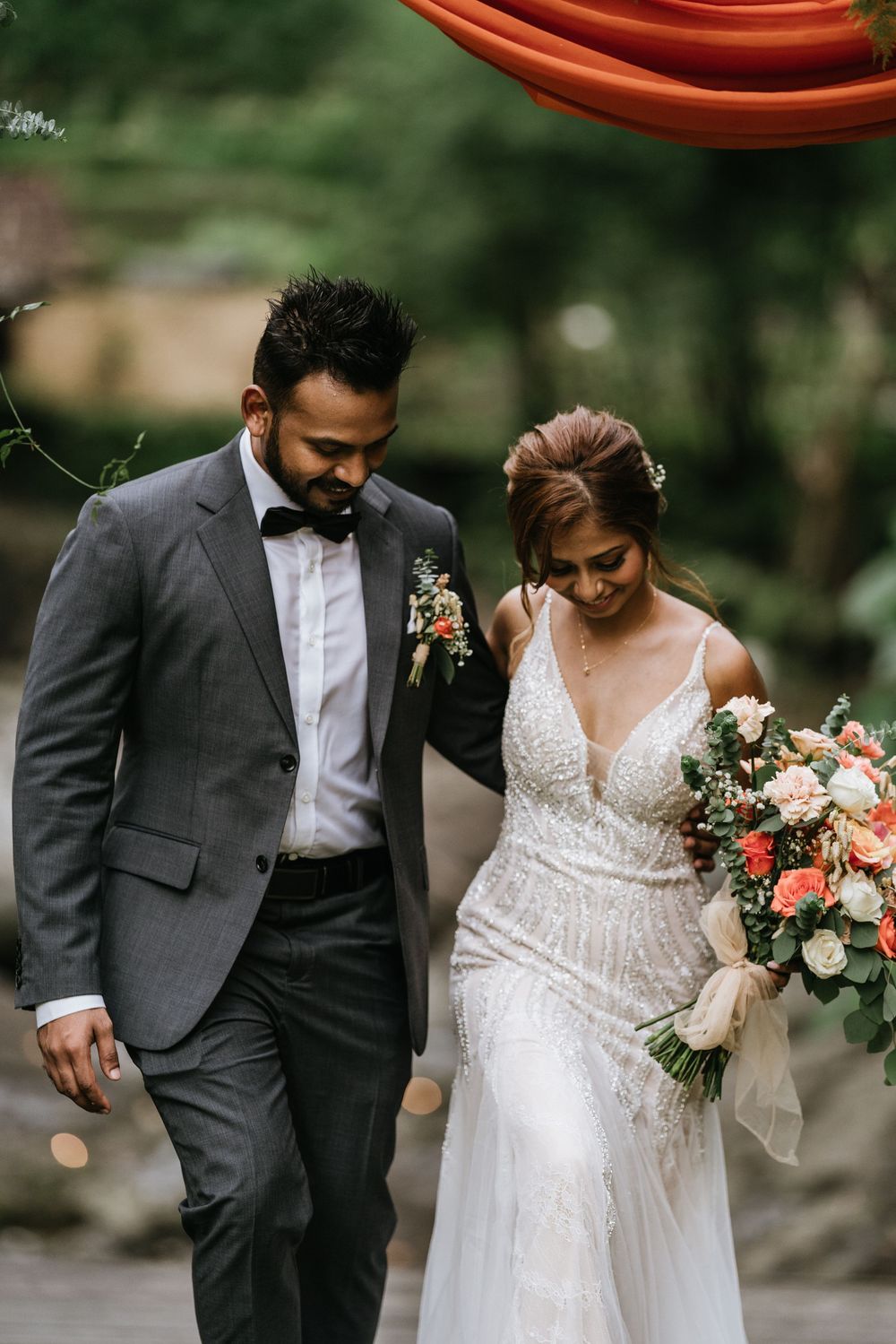 Wedding couple walking together under coral draping with elegant floral arrangements.