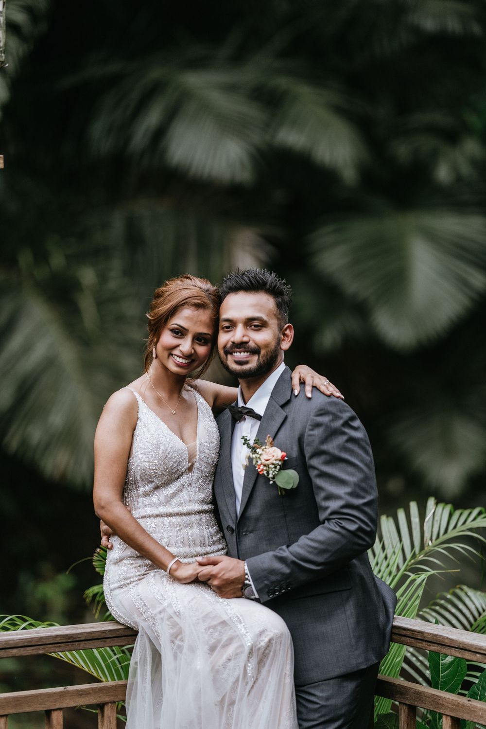 Romantic wedding portraits on wooden deck surrounded by tropical greenery.