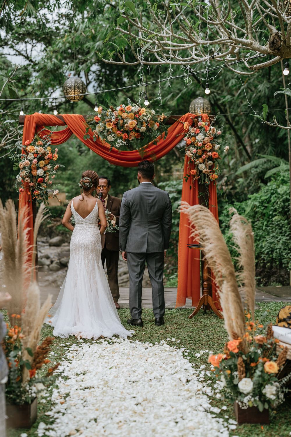 Wedding ceremony site with coral arch and white petals scattered along the aisle.