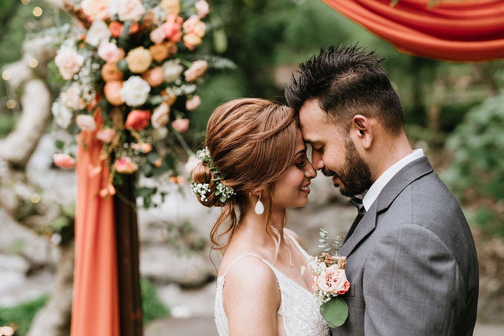 Intimate wedding ceremony moments under coral draped arch with floral decorations.