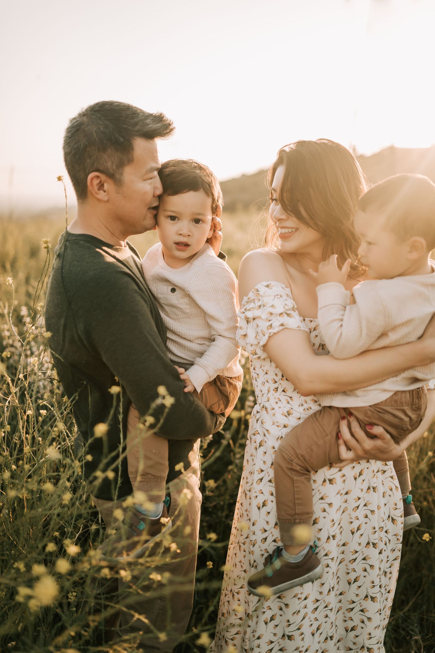A family shares an intimate moment together in a golden sunlit meadow at sunset.