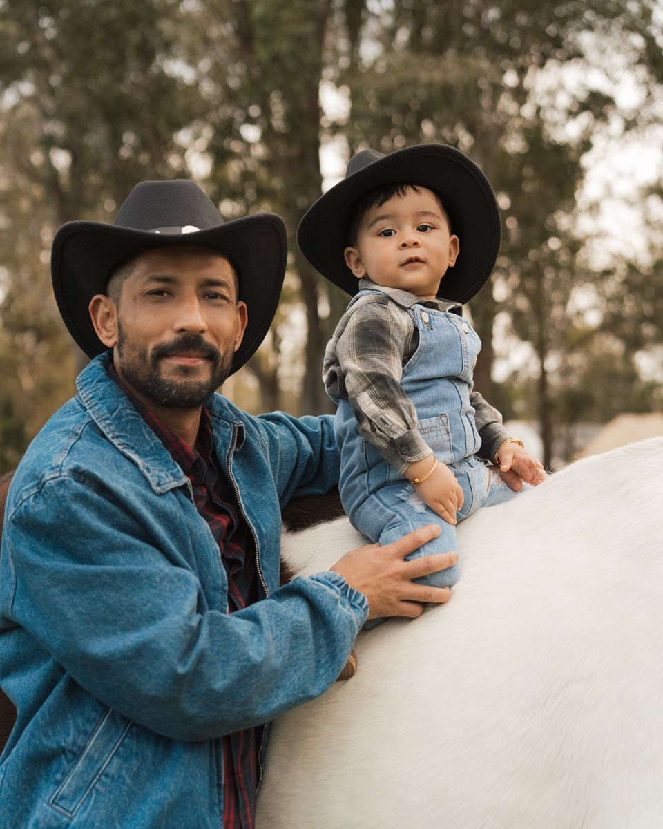 A heartwarming moment on a horse shown in a photos featuring denim jackets and cowboy hats with a dad and son during a Sydney photoshoot