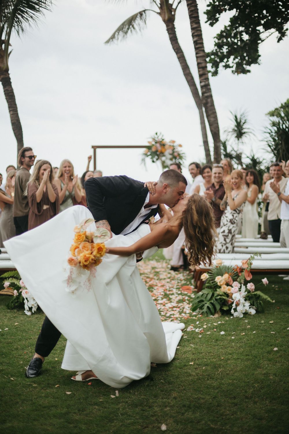Action shot of a couple dipping and celebrating at their beachside wedding ceremony in Bali