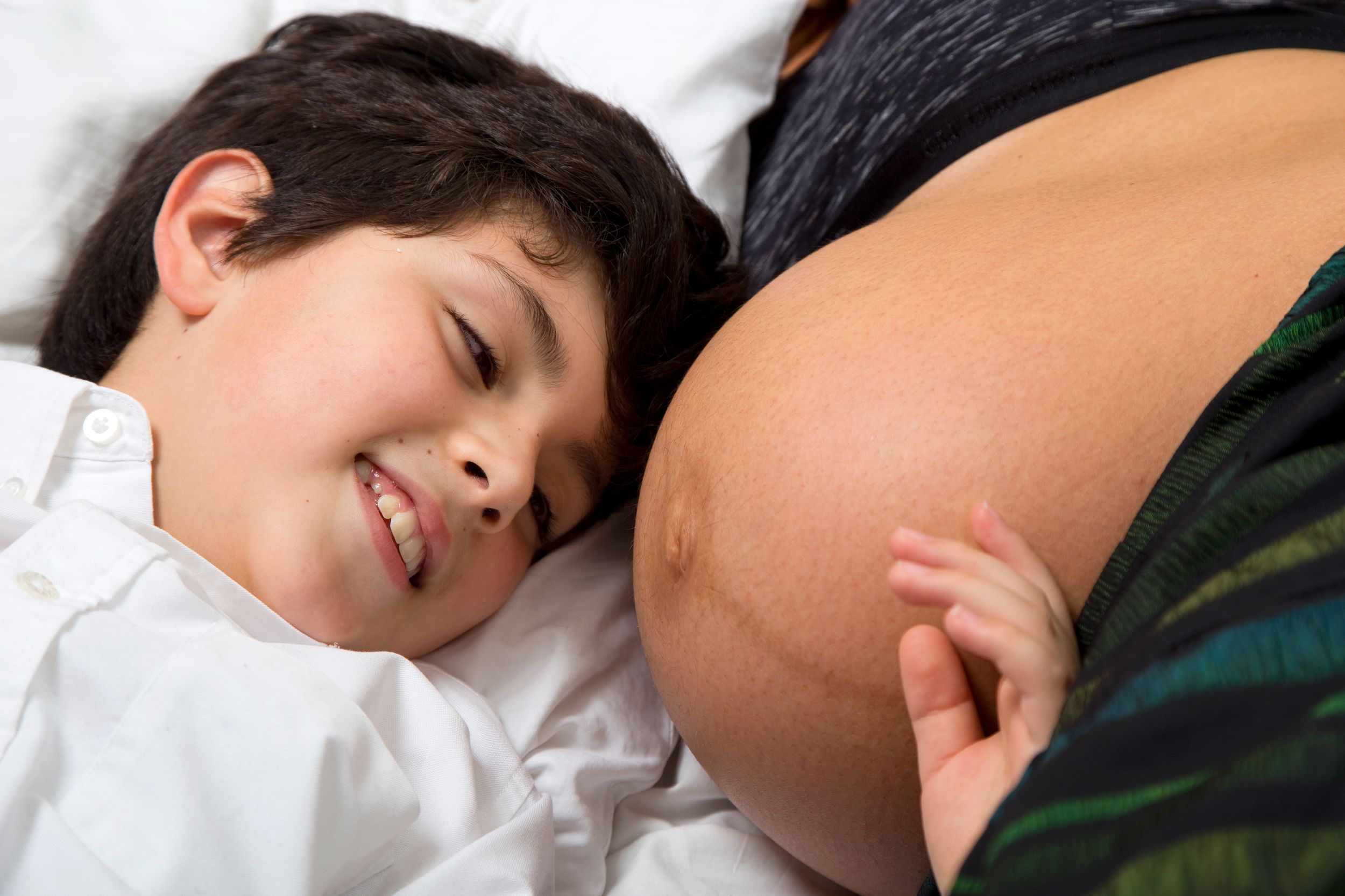 A boy poses with his mother's bump during a family photo shoot.