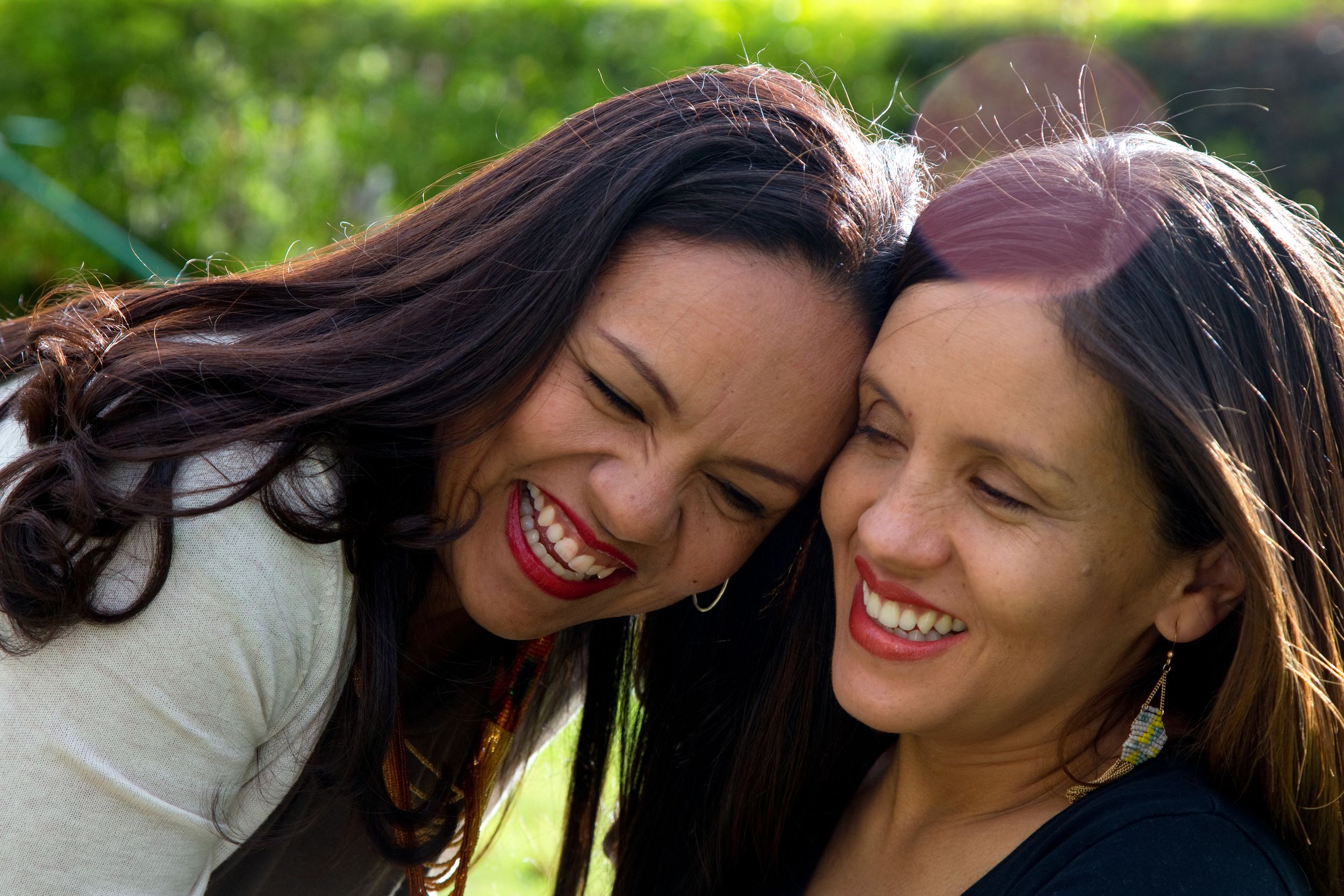 A pair of sisters laugh during a family photo shoot.