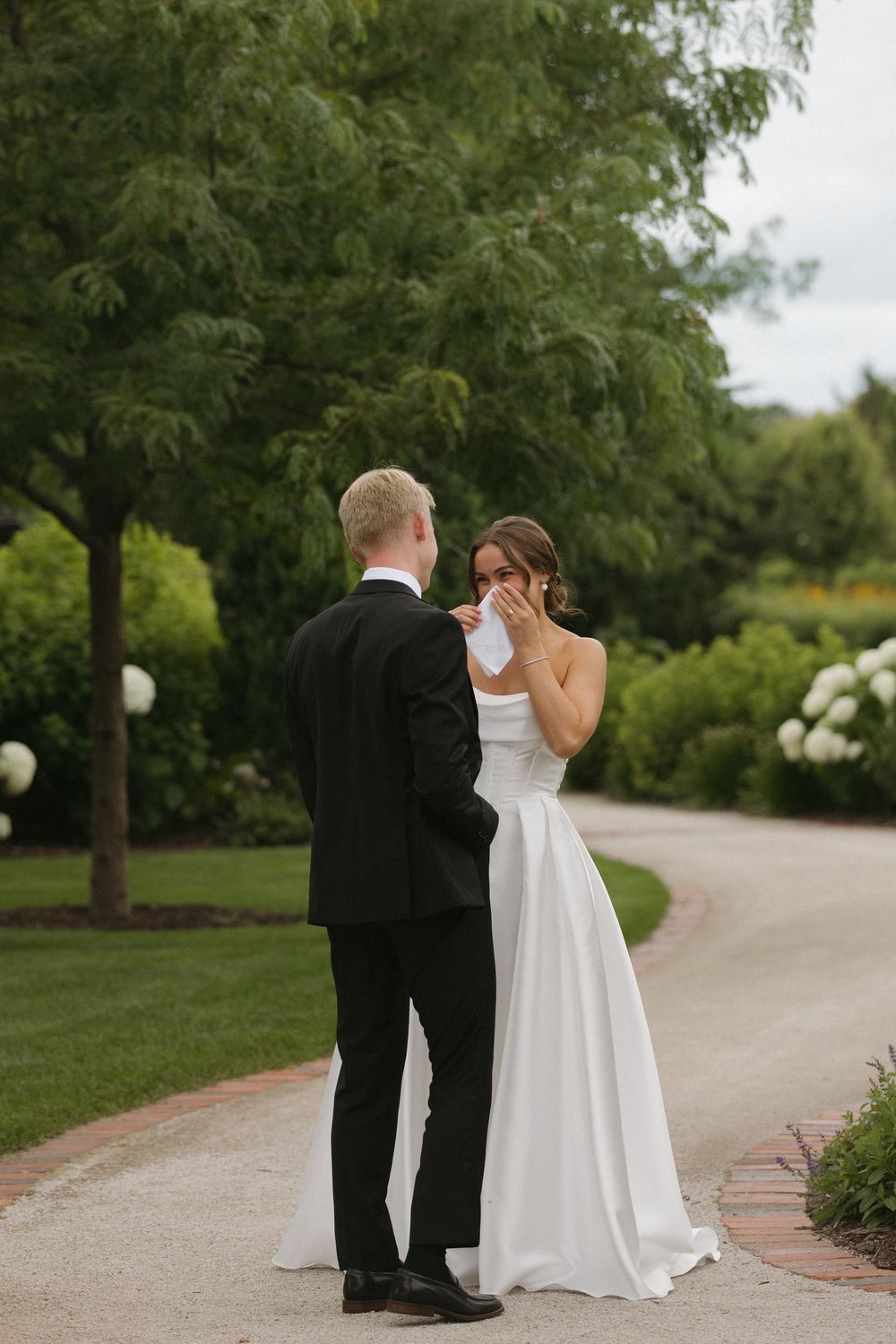 Wedding couple sharing an intimate moment on a garden path surrounded by greenery.