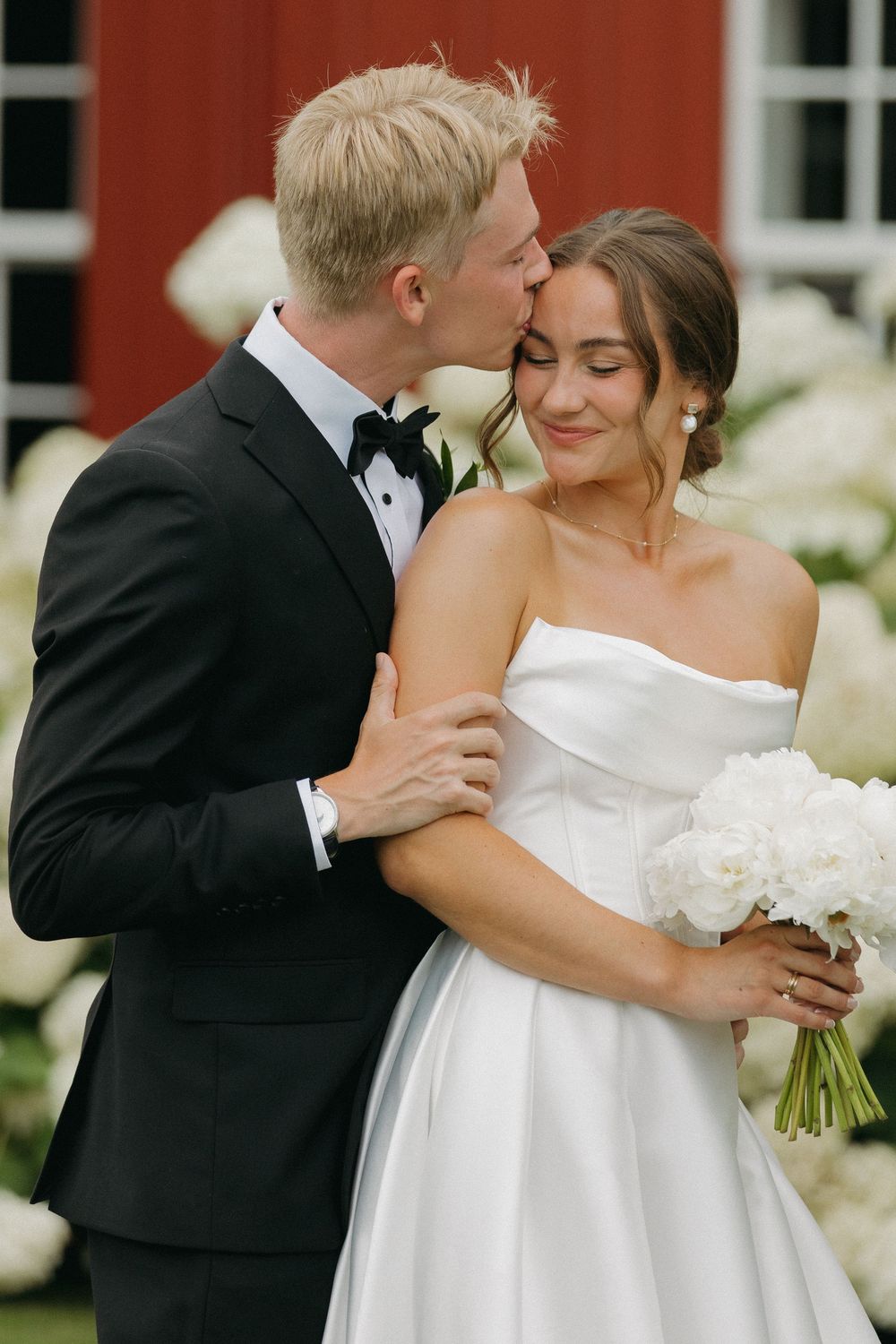 A series of intimate wedding photos showing tender moments between a bride and groom against a red barn backdrop.
