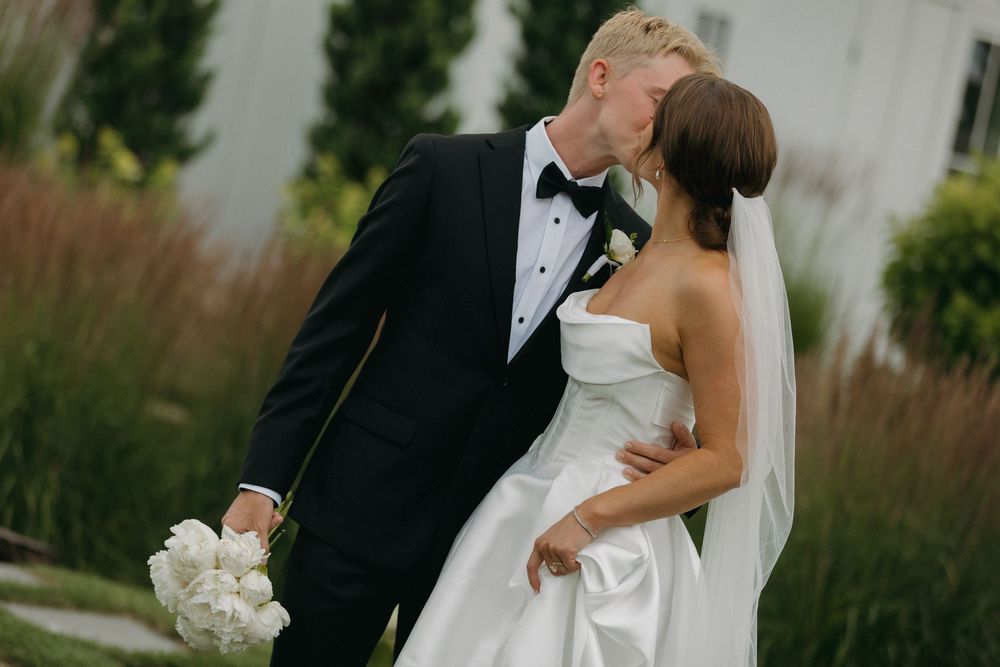 Romantic wedding moments photographed against a cloudy sky and garden landscape.