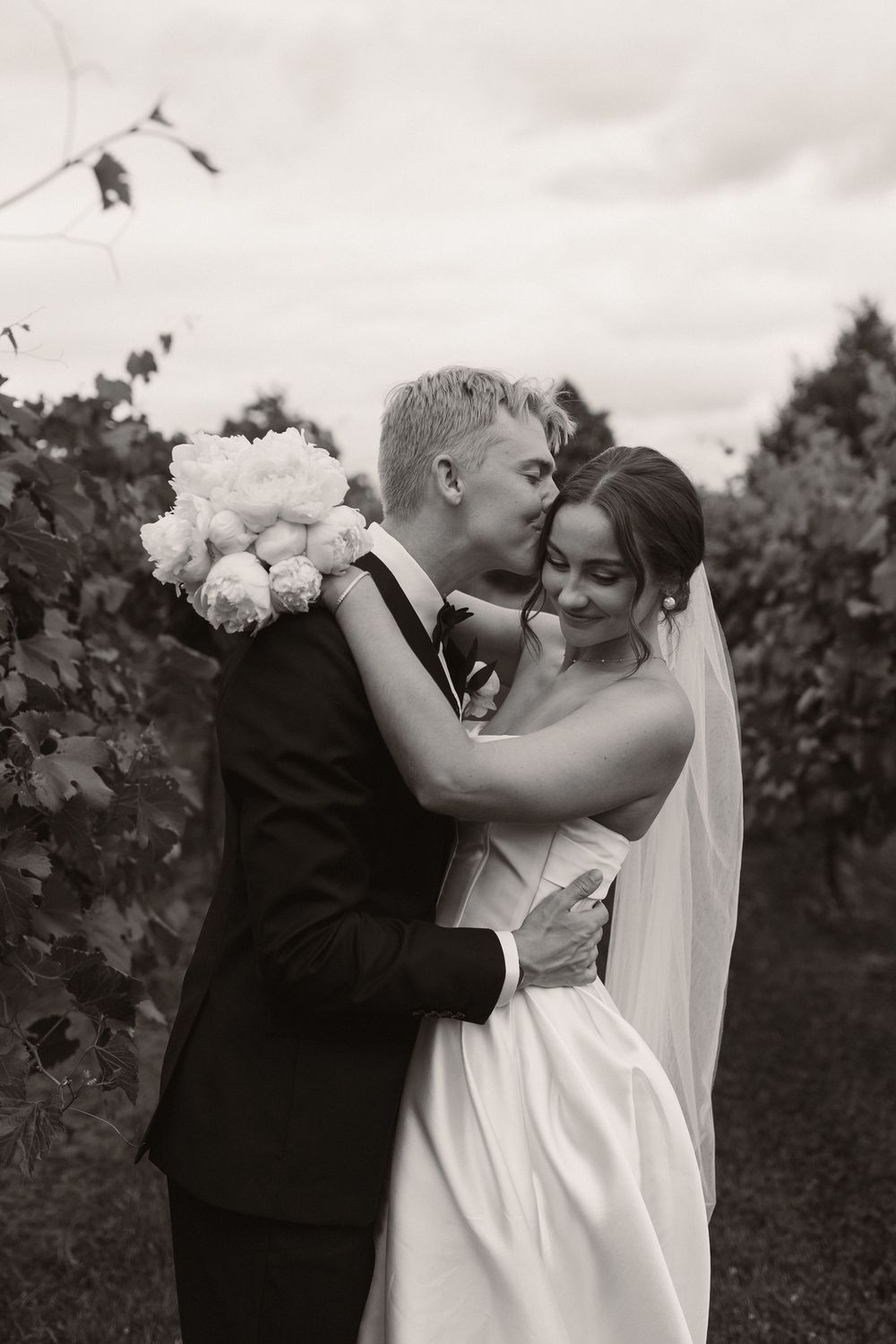 Black and white wedding portraits capturing romantic embraces in a vineyard setting.
