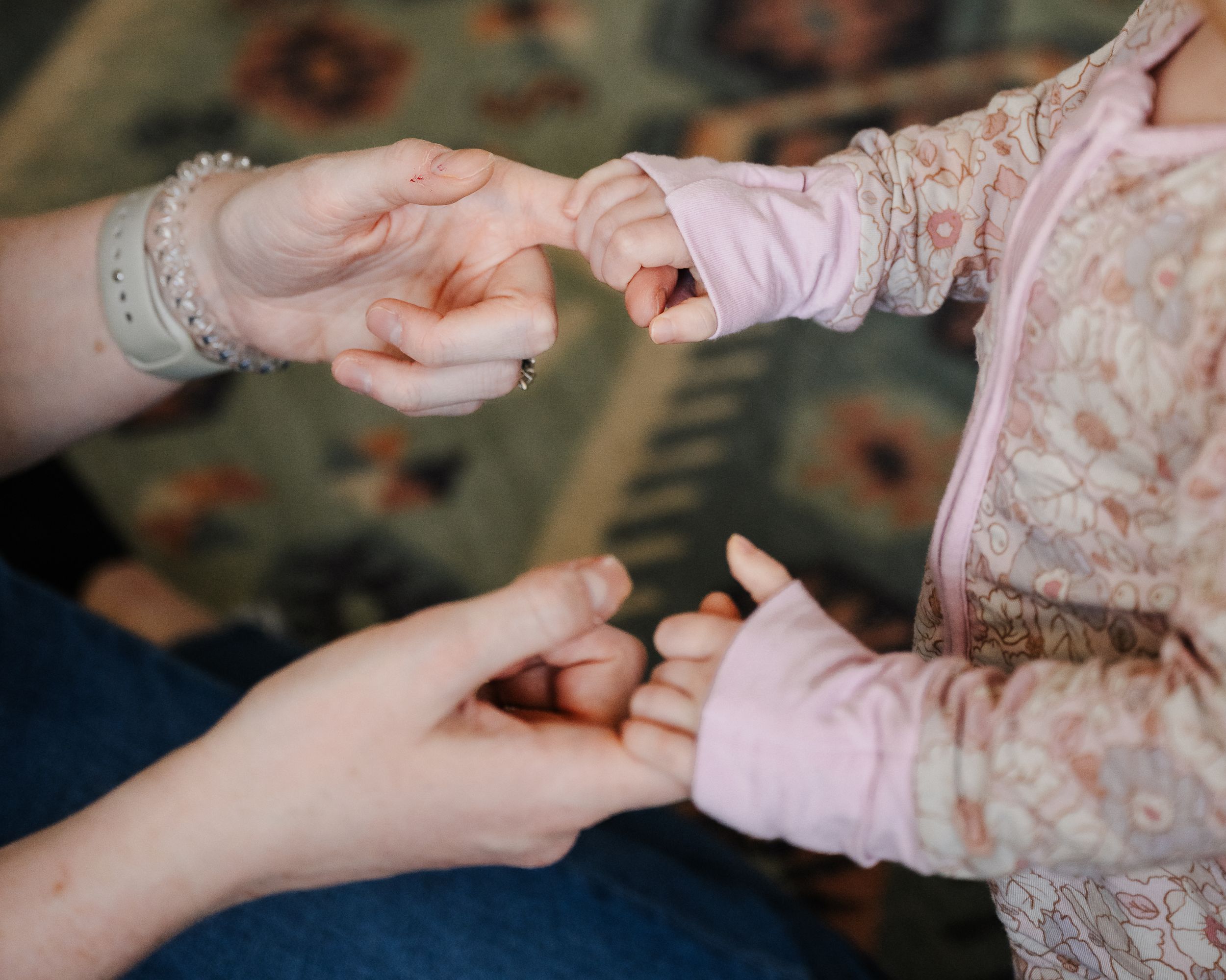 Mamas fingers and baby girls tiny hands wrapped around them.