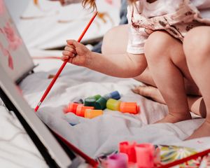 Playful lifestyle family photo—child painting on mom outdoors, capturing joy, laughter, and authentic connection.