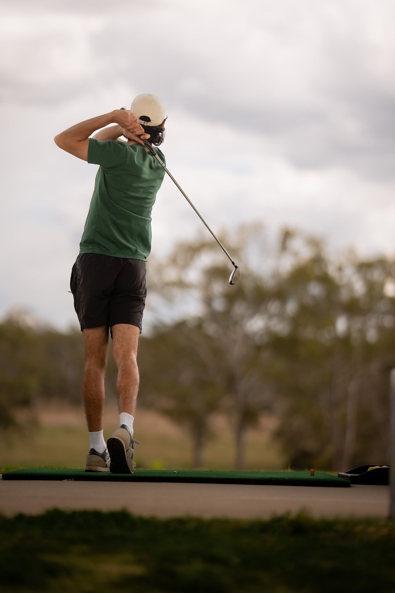 Four sequential shots of a golfer's follow-through swing motion captured at dusk on a golf course.