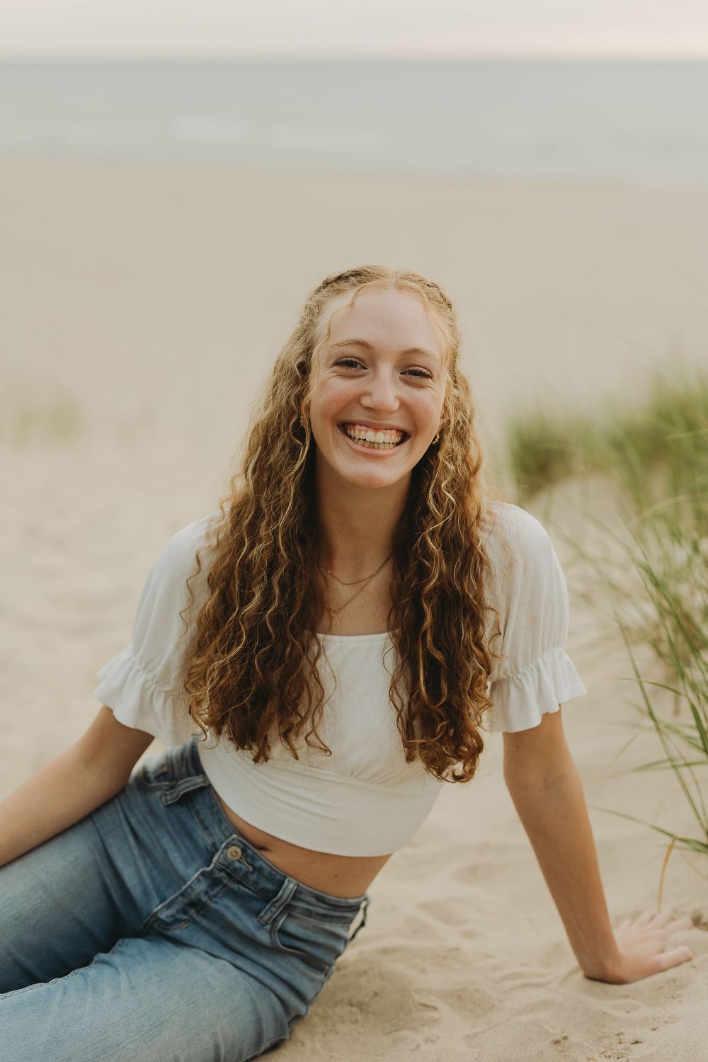A sequence of portraits showing someone with curly hair and a white t-shirt lying in beach sand with natural lighting.
