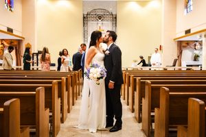 A romantic moment in a church aisle with wooden pews and stained glass windows.