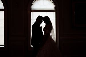 Dramatic silhouette portraits in dark interior with window backlighting.