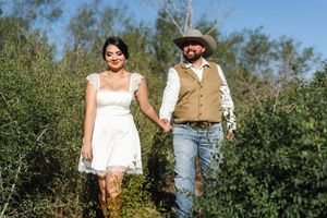 A casual countryside engagement photo with white dress and rustic attire.