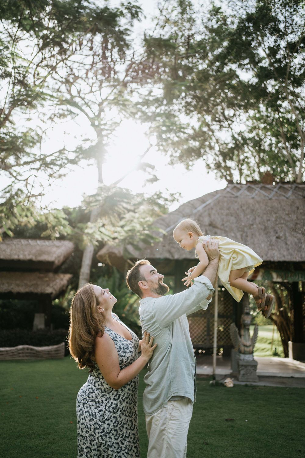 Joyful family playtime captured in a garden setting with traditional structures in the background.
