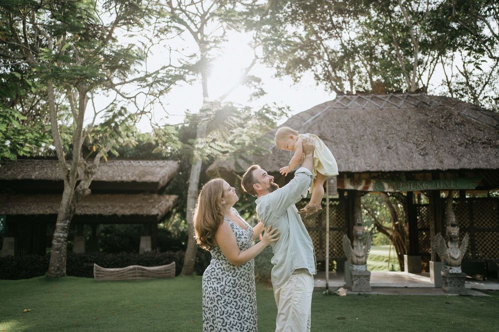 Family enjoying a playful moment together in a lush outdoor garden setting.