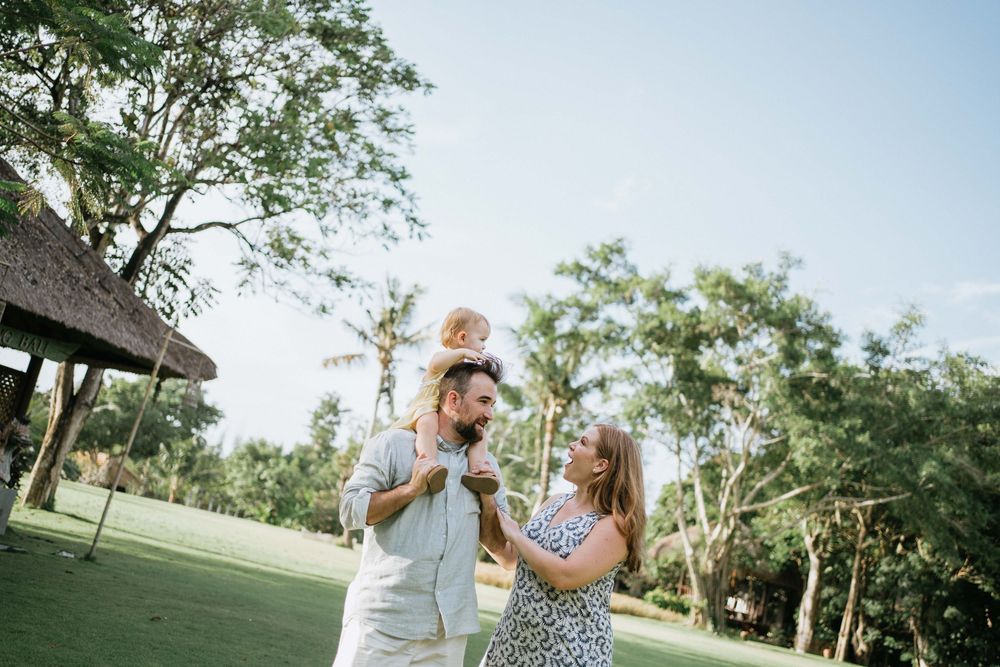 Candid family moment captured in a tropical garden with palm trees and natural greenery.