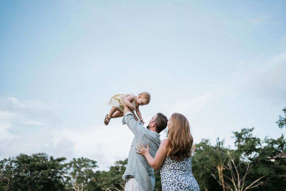 Joyful outdoor family photoshoot against a bright blue sky.
