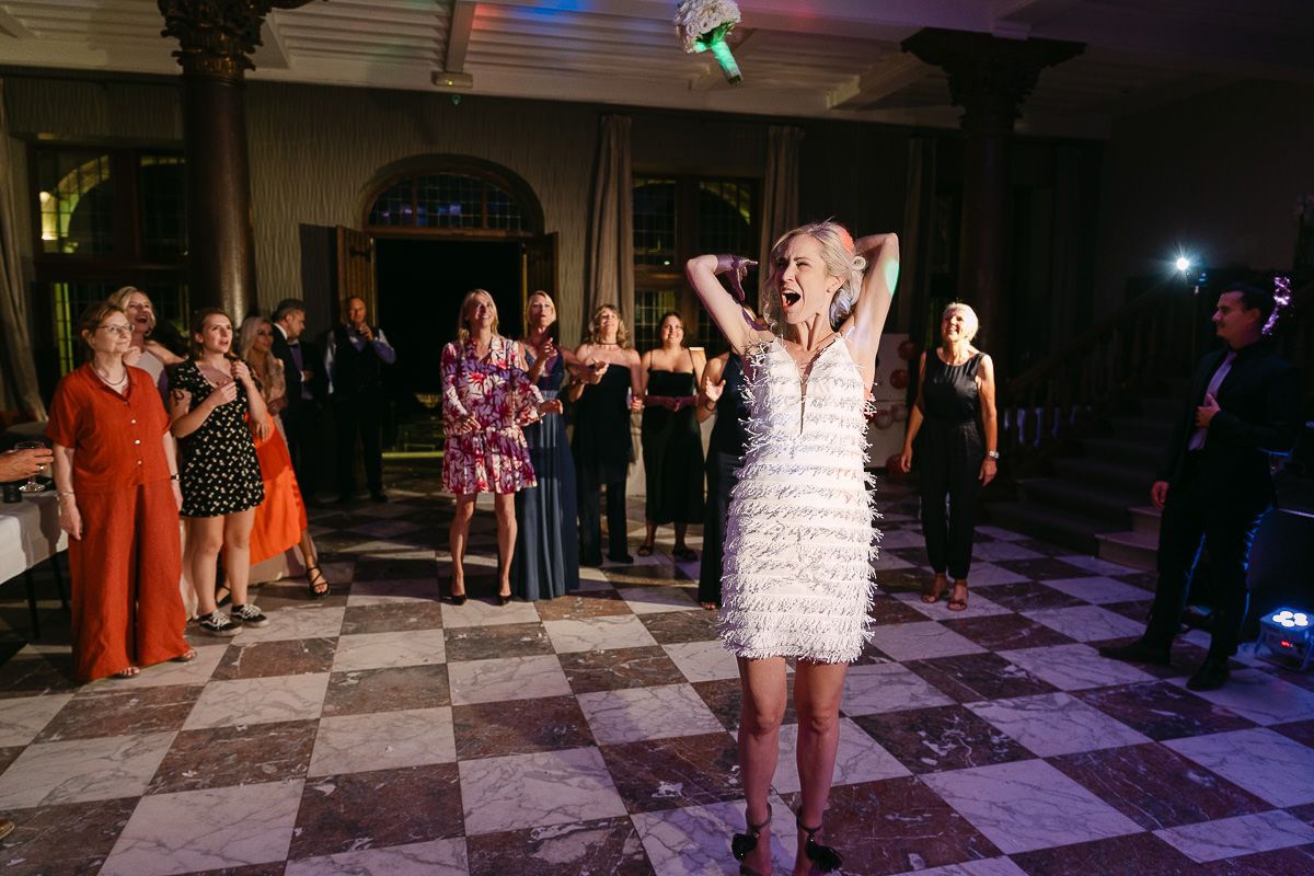 Bride throwing bouquet during wedding party at Manoir de Lébioles