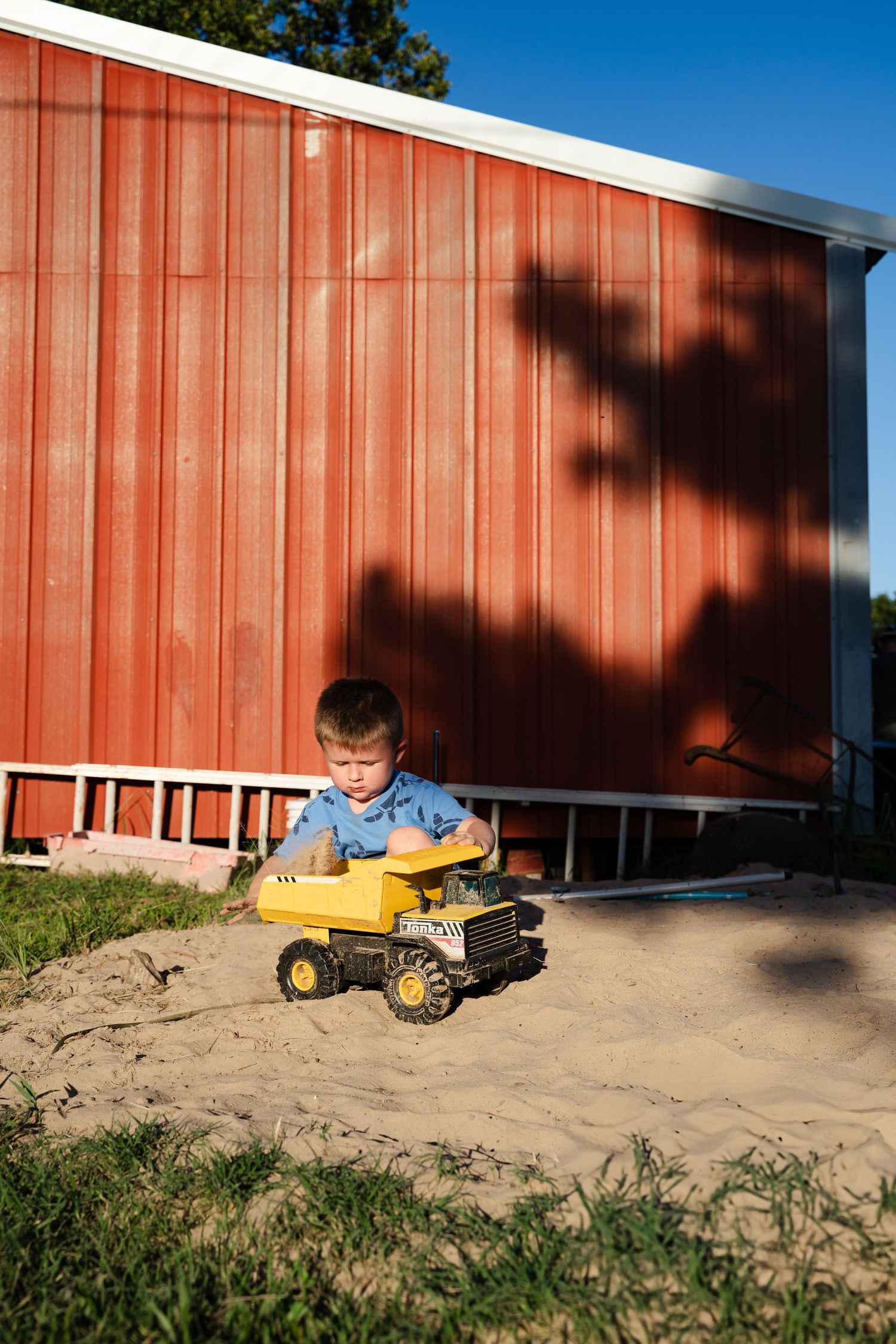 Young boy gets distracted by toy truck and sand pit during this family documentary photography session outside of Tulsa, Oklahoma
