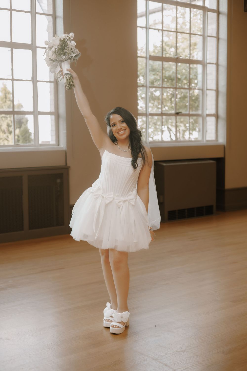 A dancer in a white tulle dress twirls gracefully across a sunlit dance studio floor.