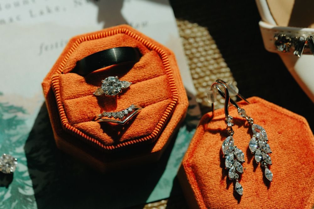A bright orange scarf with delicate silver butterfly pins arranged in a decorative pattern on the fabric.