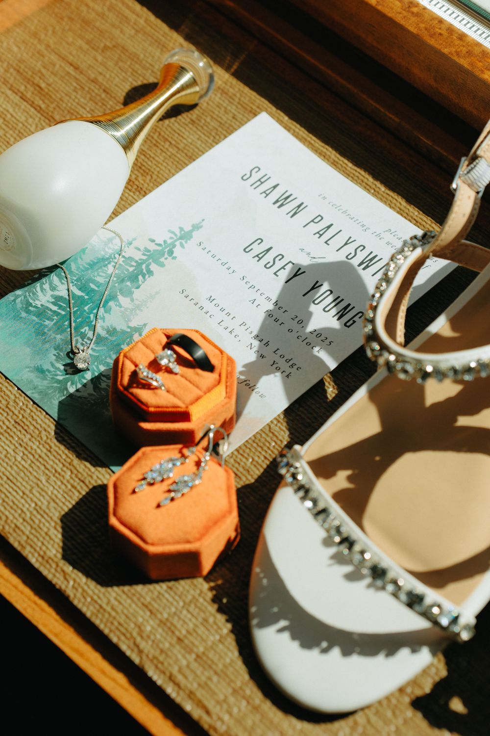 Wedding invitations and decorative elements arranged on a wooden surface with teal and coral accents.