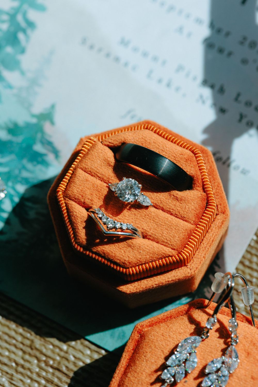 Diamond engagement ring and wedding band nestled in an orange velvet octagonal ring box.