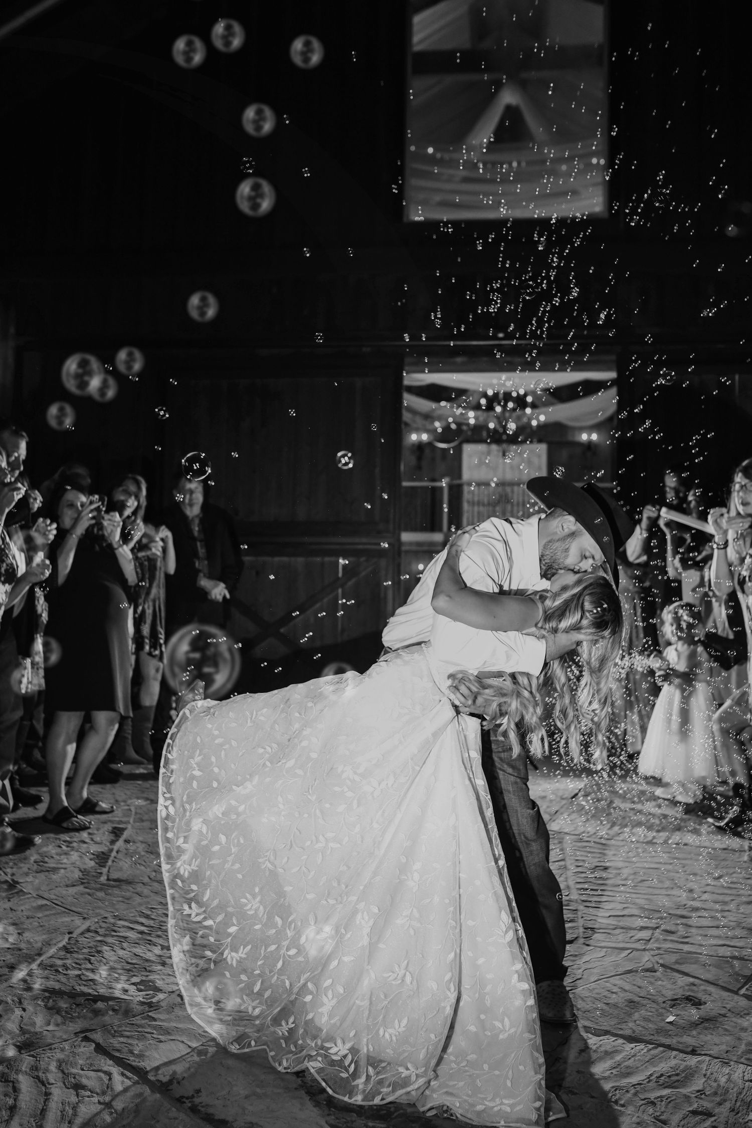 Bride and groom laughing under a cloud of bubbles during their wedding exit