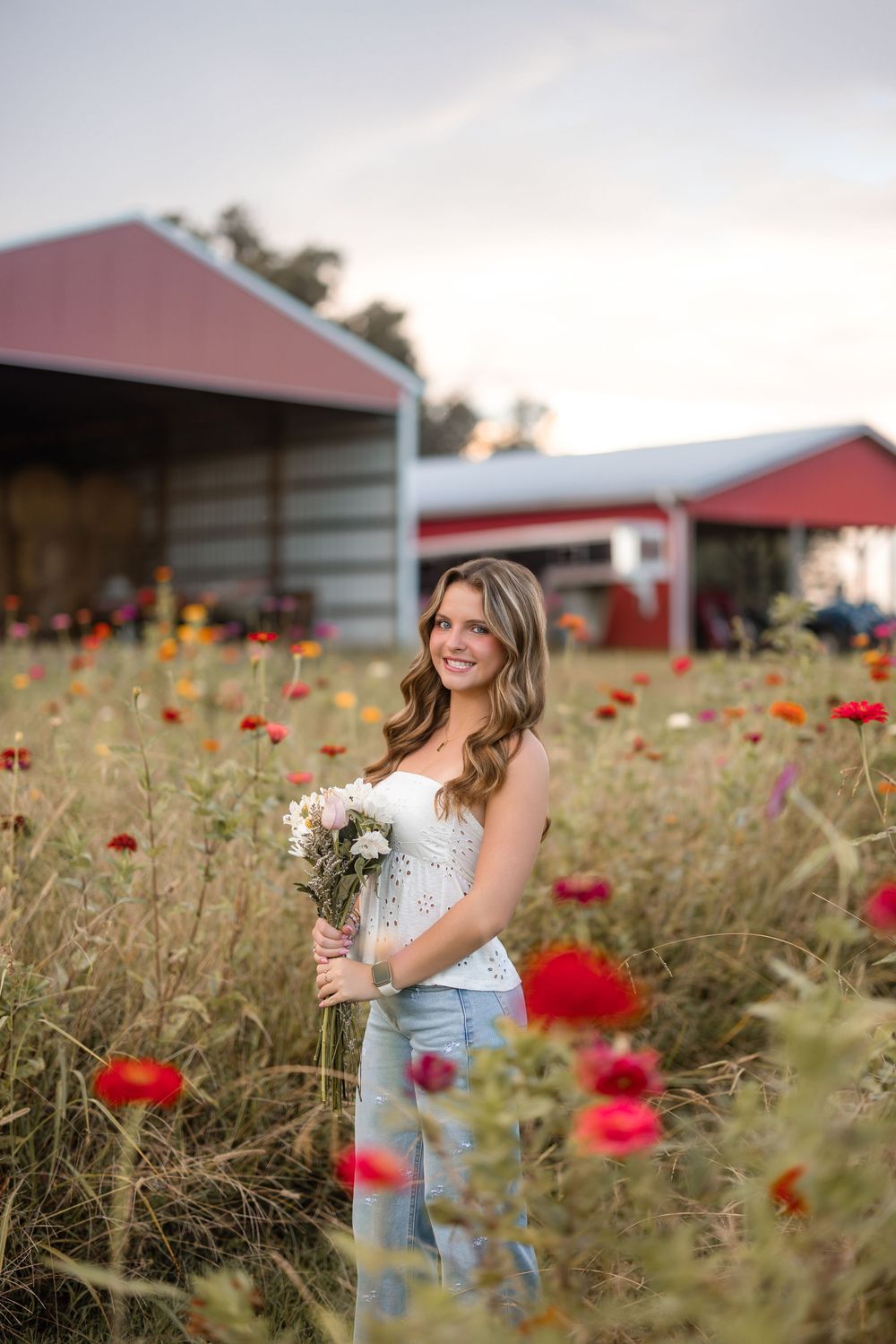 A beautiful wildflower field with red poppies and rustic barns in the background creates a dreamy country scene.
