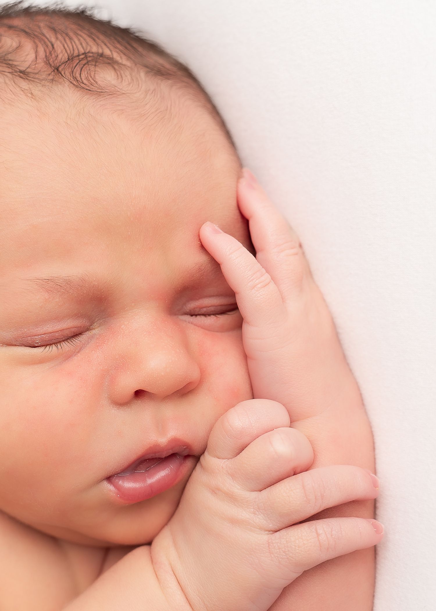 Close-up of sleeping baby's face against white background.