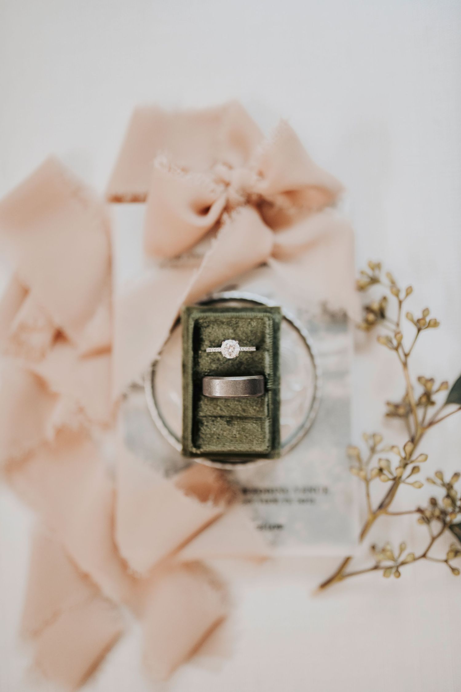 the bride and groom rings in a beautiful green velvet ring box surrounded by flowers and greenery