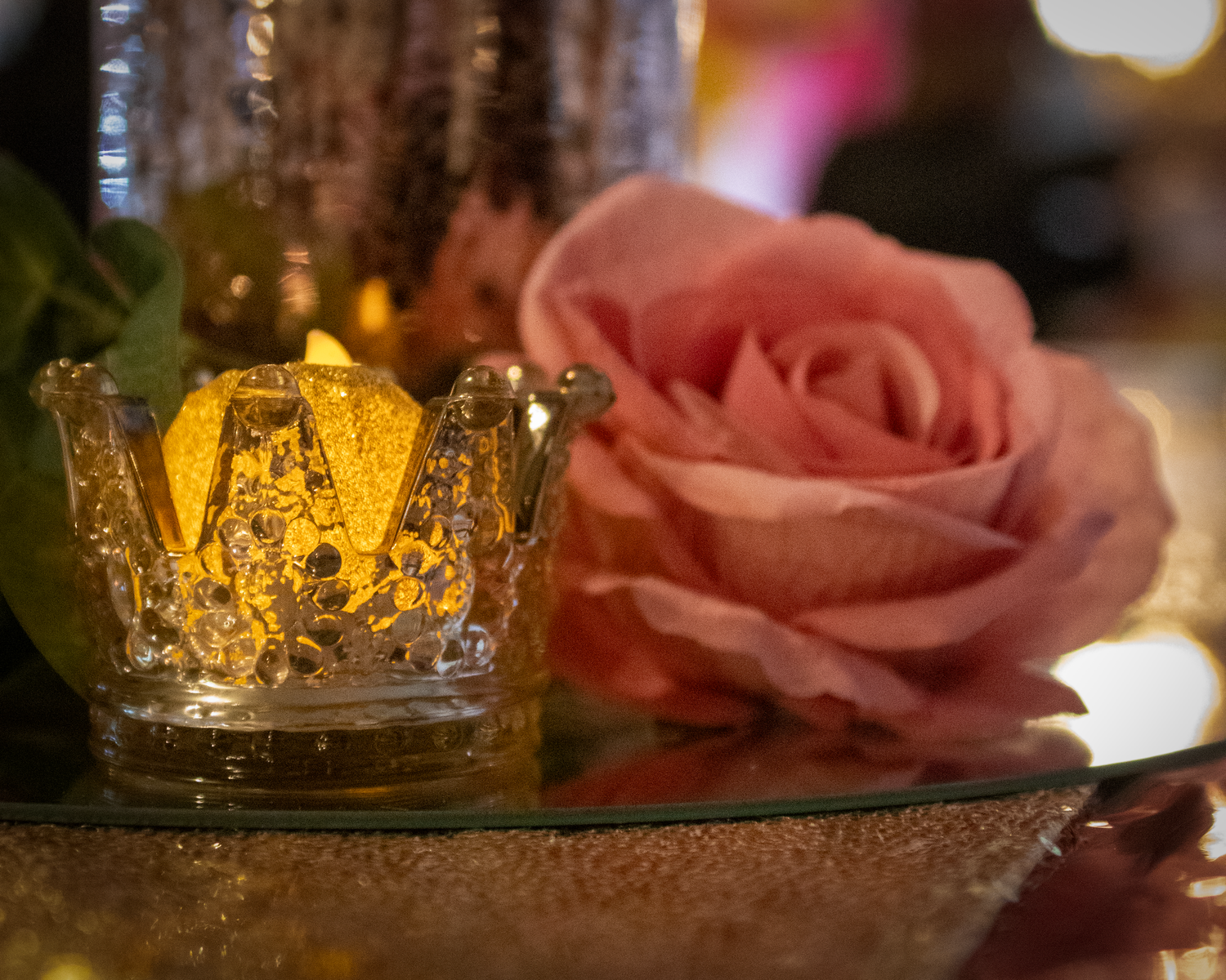Romantic table setting with pink roses and glowing candles creates an intimate dining atmosphere.