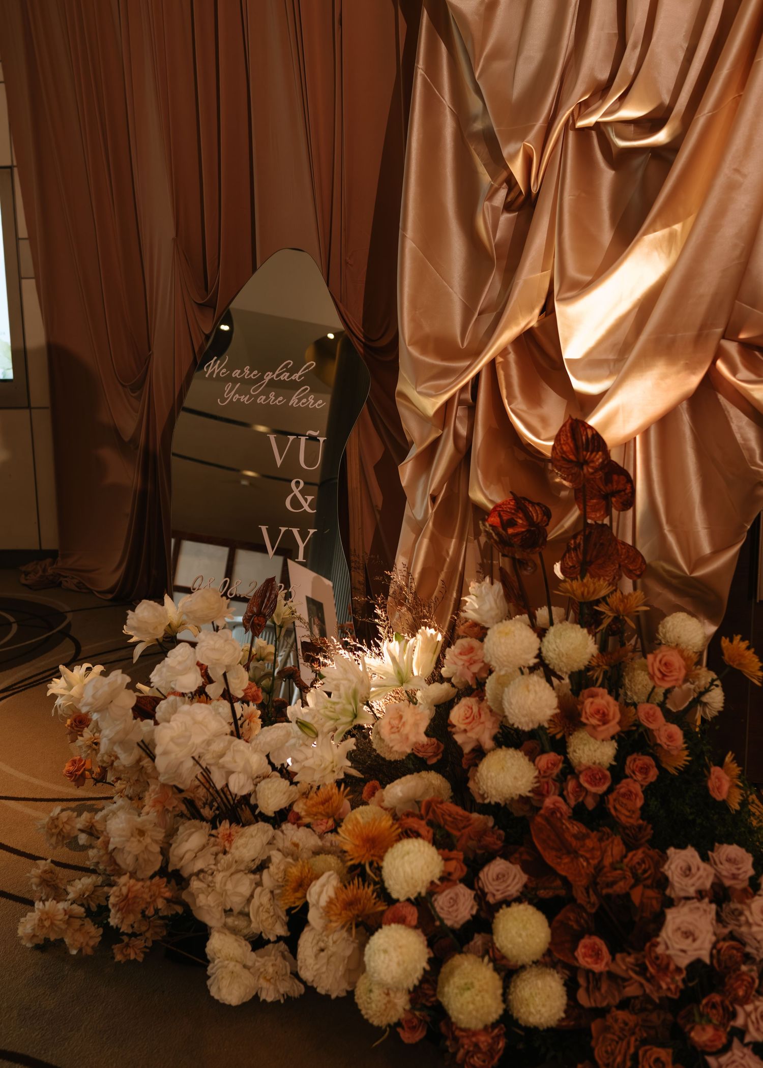 Wedding welcome mirror sign for Vu and Vy surrounded by white and terracotta floral arrangements.