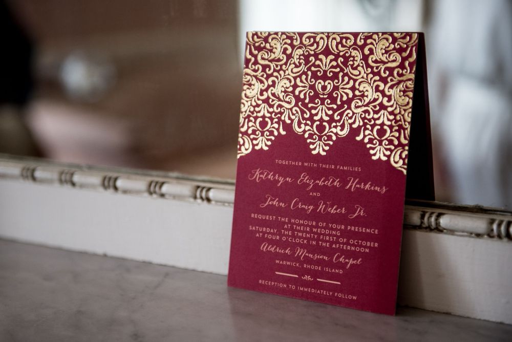 Burgundy and gold wedding invitation with ornate damask pattern design.