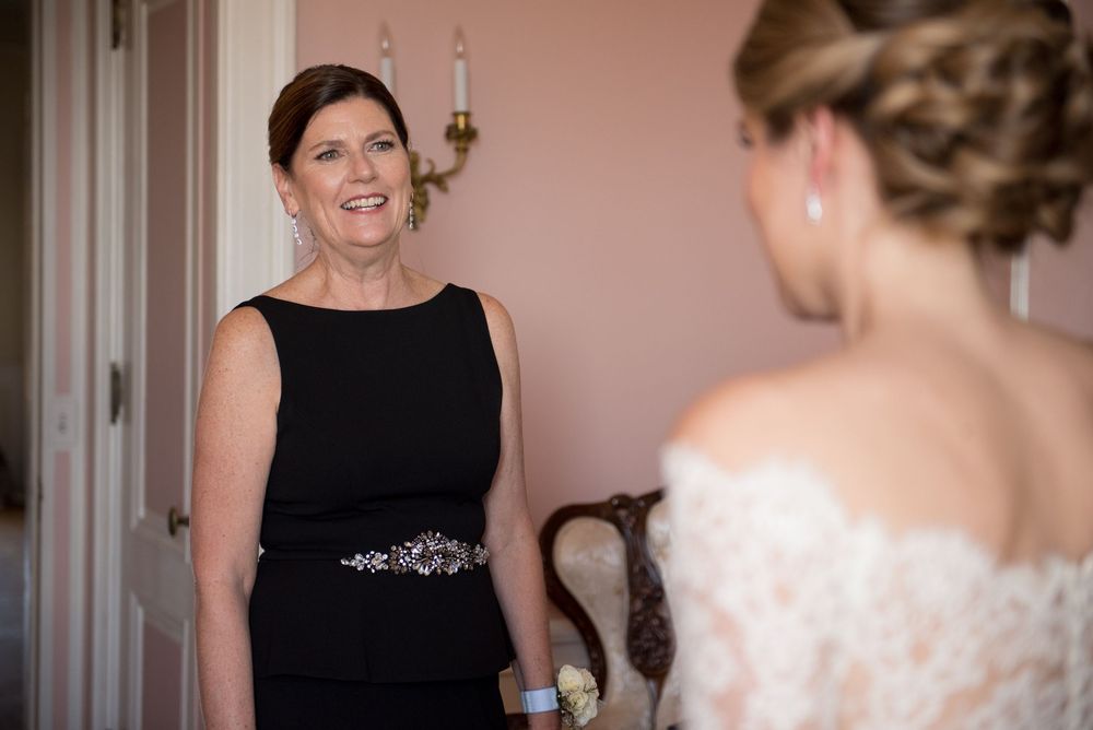 Wedding preparations in a room with pink walls and ornate chandelier.