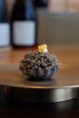 A chocolate-colored popcorn ball or crispy treat sits on a dark wooden surface, shown from various angles against a blurred background.