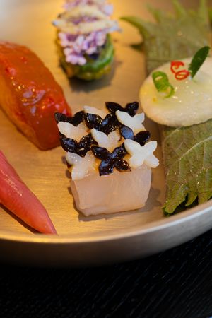 Elegant Japanese sushi nigiri pieces with black caviar garnish served on a white ceramic plate.