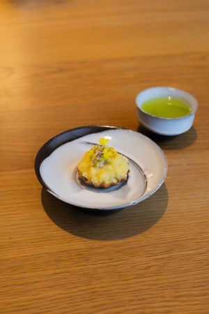 A sequence of small elegant plates with delicate garnished appetizers on a wooden table surface.