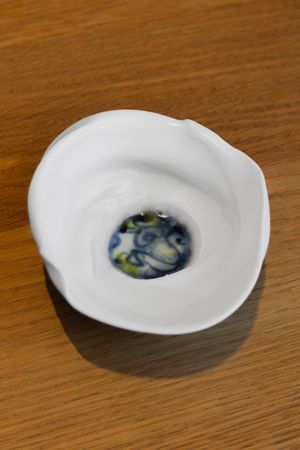 White ceramic bowl with swirled blue and white design in the center sitting on a wooden surface.