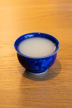 A traditional blue and white ceramic bowl filled with a cloudy white liquid on a wooden table.