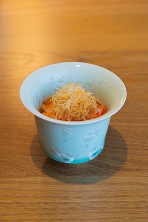 Small blue ceramic bowl filled with grated orange cheese on a wooden table.