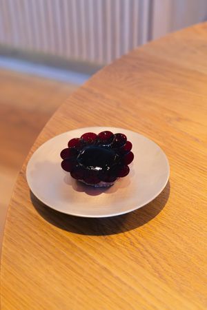 A dark purple jelly dessert with a floral shape served on a white plate.