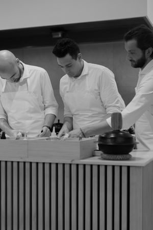 Professional chefs in white uniforms working together at a modern kitchen counter.