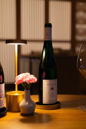 Several wine bottles arranged on a dimly lit wooden table with ambient lighting creating a cozy restaurant atmosphere.