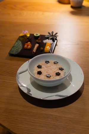 White bowl with decorative black dots arranged in artistic design on wooden table.