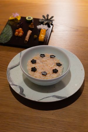 Several white ceramic plates with decorative black flower garnishes displayed on a wooden surface.